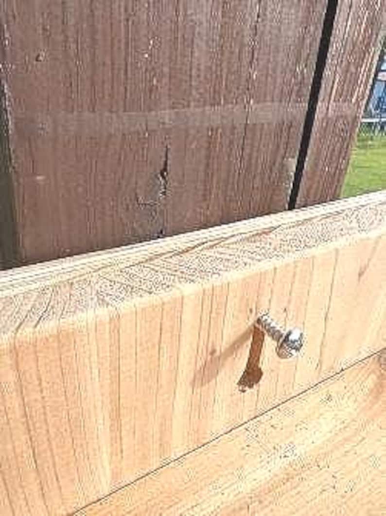 May include: Close-up of a wood surface with a silver screw. The screw is partially inserted into the wood.