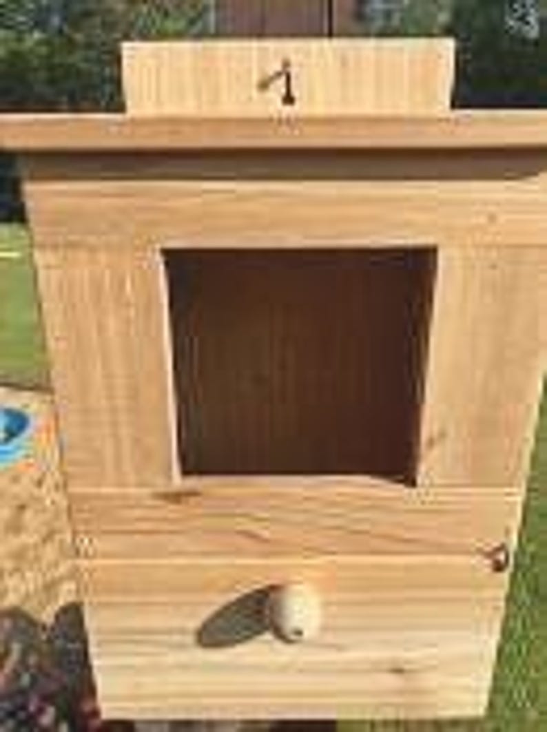 May include: A wooden birdhouse with a small opening and a number "1" on the top. The birdhouse is painted a light brown color and has a white knob on the bottom.