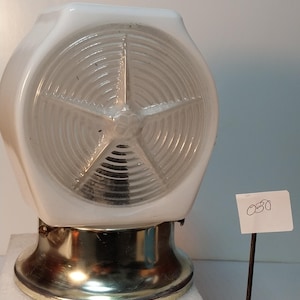 May include: A white milk glass light fixture shade with a clear glass center featuring a raised star pattern and concentric circular ridges. The shade is mounted on a metallic base with visible screws and sits next to a small tag labeled 030.