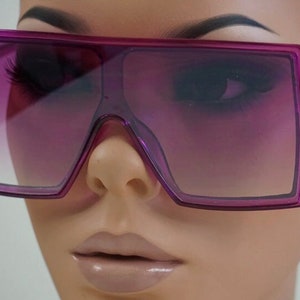 May include: Purple square-shaped sunglasses with a gradient lens. The sunglasses are on a mannequin head.