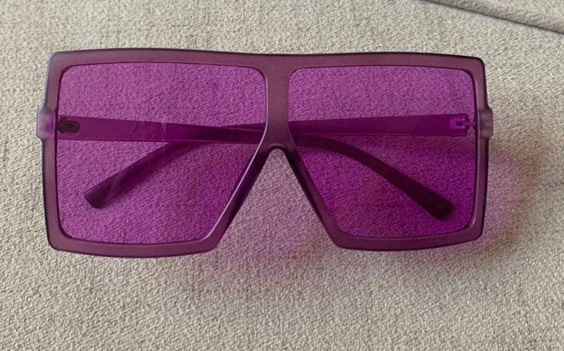May include: Purple square-shaped sunglasses with a thick frame.
