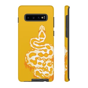 Pode incluir: Uma capa de telefone amarela com um design de cobra branca e amarela. A cobra está enrolada e tem a língua vermelha.