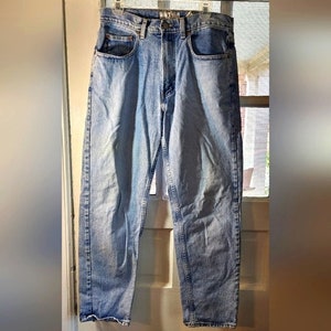 May include: Light blue denim jeans with a straight leg fit. The jeans have a classic five-pocket style and a button fly.
