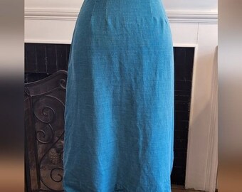 May include: A teal blue midi skirt made of a textured linen fabric. The skirt has a straight silhouette and a simple design.