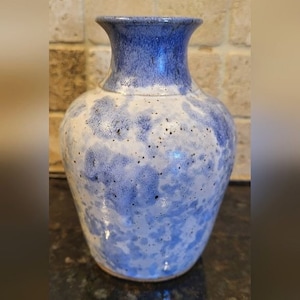 May include: A blue and white ceramic vase with a speckled glaze. The vase has a rounded body and a narrow neck.