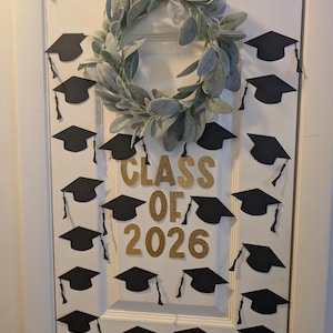 May include: A white ceramic mug with a black handle and the text "But First, Coffee" in a bold, black font. The mug is set against a blurred background, suggesting a cozy setting.