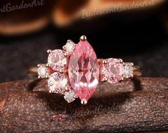 May include: A rose gold ring with a large pink marquise-shaped gemstone surrounded by smaller pink and white gemstones.