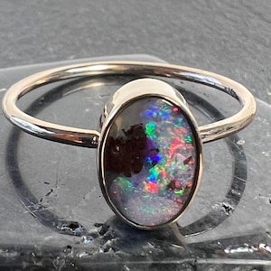 Minimalist boulder opal ring set in 14k yellow gold. Bezel set boulder opal stackable ring in 14k gold.