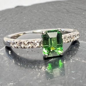 Emerald cut tsavorite garnet ring with diamond accented band set in 14k white gold.