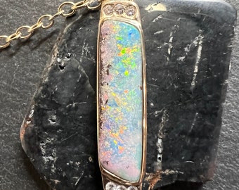 May include: A gold chain necklace with a rectangular pendant featuring a colorful opal stone surrounded by small diamonds.