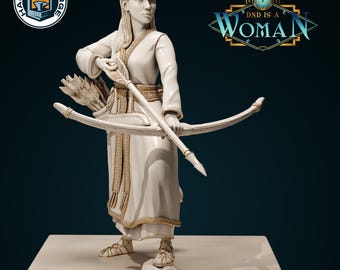 May include: A white painted figurine of a woman holding a bow and arrow. She is wearing a long white robe with gold accents. The figurine is standing on a white base. The text "DND IS A WOMAN" is visible in the background.