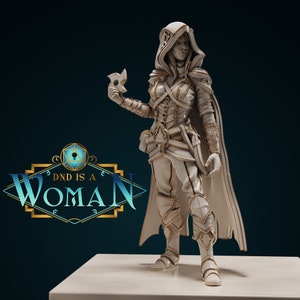 May include: White painted miniature figurine of a female character wearing a hooded cloak and holding a throwing star. The figurine is standing on a white platform. The text "DND IS A WOMAN" is visible in the background.