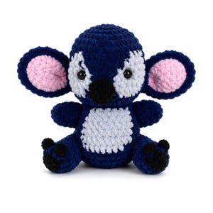 Puede incluir: Un peluche de koala hecho a mano de ganchillo azul y blanco con el interior de las orejas rosa y detalles negros. El koala tiene una barriga blanca y est&aacute; sentado con los brazos y las piernas extendidos. El juguete est&aacute; hecho de hilo suave.