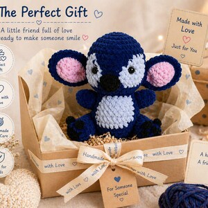 Puede incluir: Un juguete de peluche de ganchillo azul y rosa hecho a mano, presentado en una caja de regalo con una cinta que dice "with Love". La caja incluye una etiqueta que dice "For Someone Special".