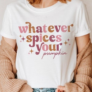 May include: White t-shirt with the text "whatever spices your pumpkin" in pink, brown, and orange lettering with small gold stars.