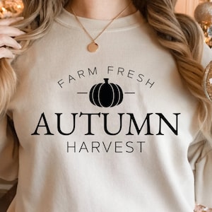 May include: A beige sweatshirt with black text that reads "Farm Fresh - Autumn Harvest" with a black pumpkin graphic.