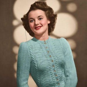 May include: A light blue long-sleeved cardigan featuring a vertical cable knit pattern and a delicate openwork design. The garment has a round neckline and a front button closure with small, round, light-colored buttons along the center placket.