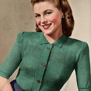 May include: Vintage green knitted blouse with a collared neckline and three-quarter sleeves. The blouse features a button-down front and a textured knit pattern. The image includes the text "Lady's Blouse" and the brand name "Munrospun".
