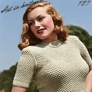 May include: A short-sleeved, light beige knit sweater featuring a textured, raised dot pattern throughout the body and sleeves. The garment has a ribbed crew neckline and a wide, ribbed waistband. The text "Art in knitwear" and "187" appear above.