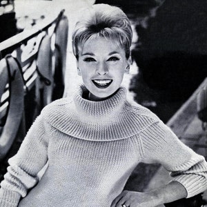May include: A close-up of a woman wearing a white turtleneck sweater. The sweater has a ribbed texture and a slightly rolled collar.
