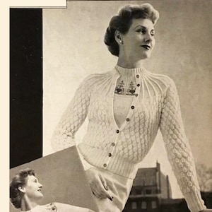 May include: Two women wearing white knitted sweaters with a cable knit pattern. The sweaters have a high neckline and a button closure. The sweaters are both short-sleeved and have a delicate lace trim around the neckline.