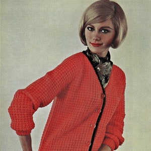May include: A red knitted cardigan with a black trim and buttons. The cardigan has a waffle knit texture and a V-neck.