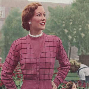 Może przedstawiać: Różowy kardigan z czarnym wzorem w kratkę i dopasowaną różową bluzką. Kardigan ma dekolt w kształcie litery V i guziki z przodu. Modelka nosi czarną spódnicę.