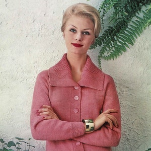 Op de afbeelding: Een roze gebreide cardigan met een brede kraag en knoopsluiting. De cardigan heeft een textuur gebreid patroon en wordt gedragen door een vrouw met blond haar.