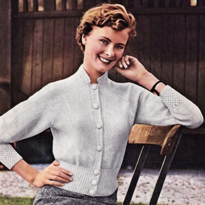 May include: A white knitted cardigan with a button-up front and a ribbed collar. The cardigan has long sleeves with a textured pattern on the cuffs.