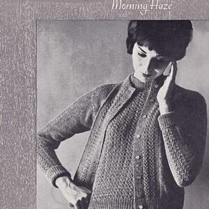 May include: A black and white photo of a woman wearing a knitted cardigan and matching top. The cardigan has a lace pattern and the top is a simple knit. The text "Munrospun Morning Haze" is printed at the top of the image. The text "Classic Twin Set in Lace Pattern and st.st. Sizes 34, 36 and 38 ins." is printed at the bottom of the image.