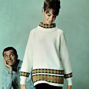 May include: A white sweater with a green, orange, and black geometric pattern around the neckline and hem. The sweater has a high neckline and long sleeves.