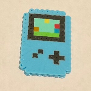 May include: A blue and black pixel art Game Boy with a green, blue, red, and yellow pixelated game screen.
