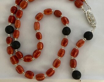 May include: A red and black rosary with lava rock beads and a silver crucifix.