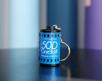 May include: A blue and black film canister keychain with the text "50D CineStill fine grain color film" and "B 50/18° Daylight 5500K".