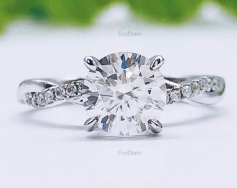 May include: A silver engagement ring with a large, round, clear diamond centre stone and smaller diamonds set in the band. The band is twisted and features a delicate design.