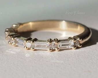 May include: A gold band ring with a row of small, clear baguette-shaped diamonds set in the band.