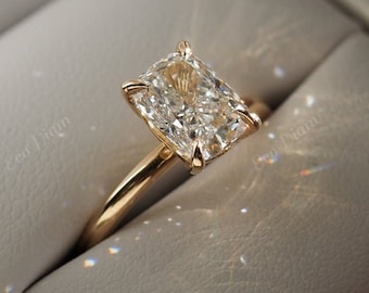May include: A radiant-cut diamond ring with a gold band, presented in a white ring box. The diamond is the focal point, reflecting light. The ring is held in a box, suggesting a special occasion.