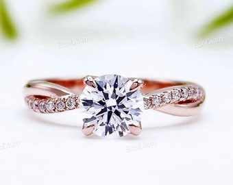 May include: A rose gold engagement ring featuring a round brilliant cut diamond centre stone and a twisted band accented with smaller diamonds.
