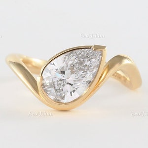 May include: A pear-shaped diamond engagement ring set in a gold band with a twisted design.