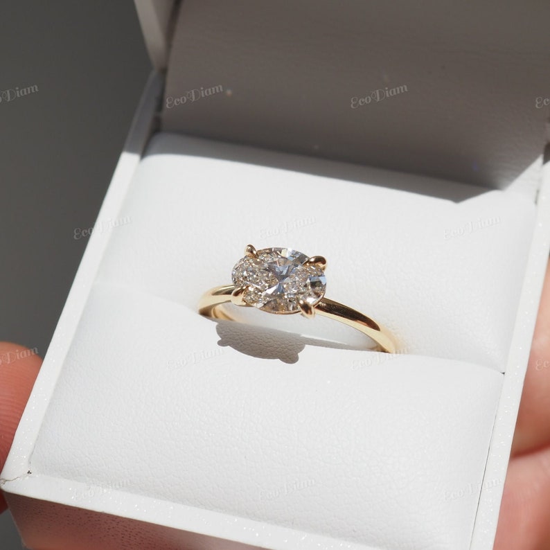 May include: A gold engagement ring with a large oval-shaped diamond surrounded by smaller diamonds.
