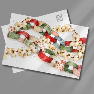 May include: A postcard featuring a watercolor illustration of a festive garland made of interlocking paper chain links in red, green, and cream patterns, interspersed with strings of popcorn. The top right corner includes a small box labeled PLACE STAMP HERE.