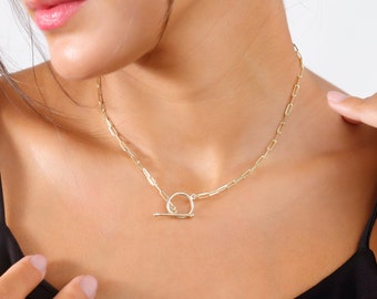 May include: A gold chain necklace with a toggle clasp. The chain is made of small, linked ovals.