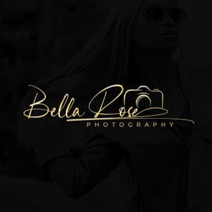 Può includere: Logo dorato con scritta "Bella Rose Photography" con icona fotocamera. Il testo è in uno stile di scrittura fluida, con la parola "Photography" in un carattere sans-serif più piccolo sotto. Lo sfondo è nero.