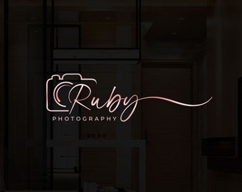 May include: A pink and white logo for a photography business called "Ruby Photography". The logo features a stylized camera icon and the name "Ruby" written in a cursive font.
