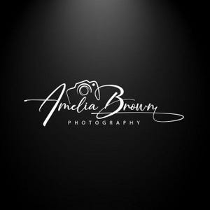 Può includere: Un logo grafico bianco su sfondo nero che presenta il testo Amelia Brown in corsivo con un'icona di fotocamera stilizzata integrata nelle lettere e la parola PHOTOGRAPHY stampata in un carattere sans-serif sotto la firma principale.