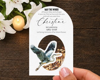 May include: A white arched memorial card featuring the text MAY THE WINDS of heaven blow and whisper in your ear that we love and miss you, and wish you were here, the name Christine Richardson, dates 1965-2026, and a blue heron illustration.