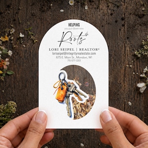 May include: An arched white card featuring the text HELPING you put down new Roots, LORI SEIPEL | REALTOR, loriseipel@integrityrealestate.com, 675 E. Main St., Mondovi, WI, 715-577-1253, with a cutout displaying a watercolor illustration of keys.