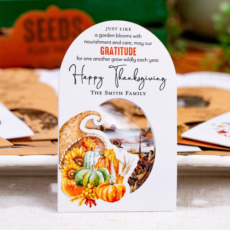 May include: A white arched seed packet featuring a watercolor cornucopia filled with pumpkins, sunflowers, and autumn leaves. The text reads: Just like a garden blooms with nourishment and care, may our gratitude for one another grow wildly each year. Happy Thanksgiving. The Smith Family.