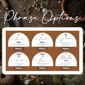 May include: A rectangular display featuring six semi-circular white labels on a brown background, each with black text and a small bee graphic. The labels show phrases like Let Love Grow, Let Love Bloom, Love Is Grown, Spread The Love, Meant To Bee, and The Adventure Begins, along with names and dates.
