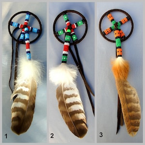 Può includere: Tre acchiappasogni perlati con piume. Gli acchiappasogni sono realizzati con perline nere, rosse, bianche, blu, verdi e arancioni. Le piume sono marroni con strisce bianche.